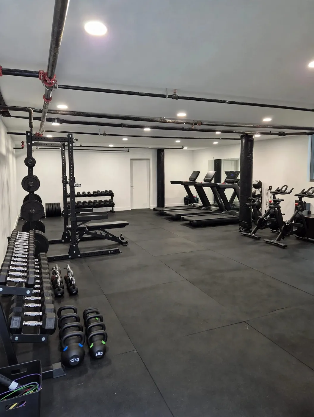Resident fitness center with treadmills, free weights, and squat racks on black rubber flooring